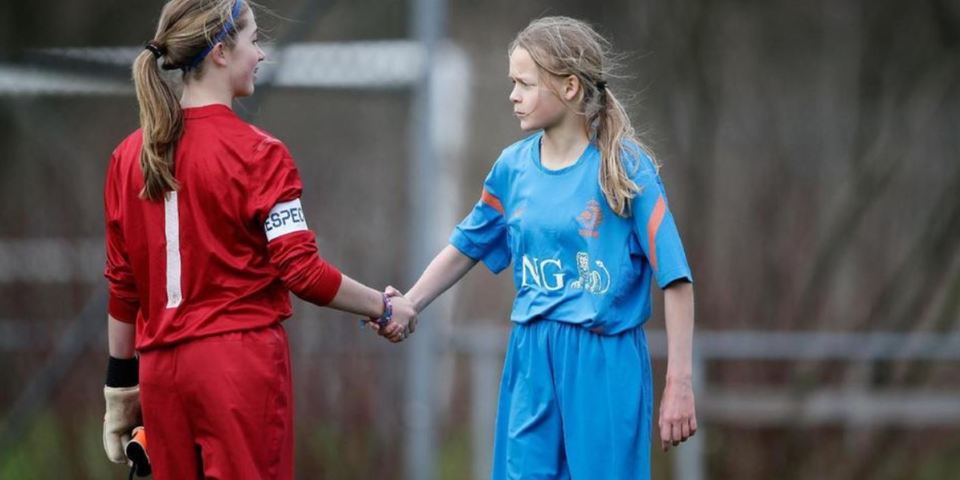 Twee voetballende meisjes geven elkaar de hand